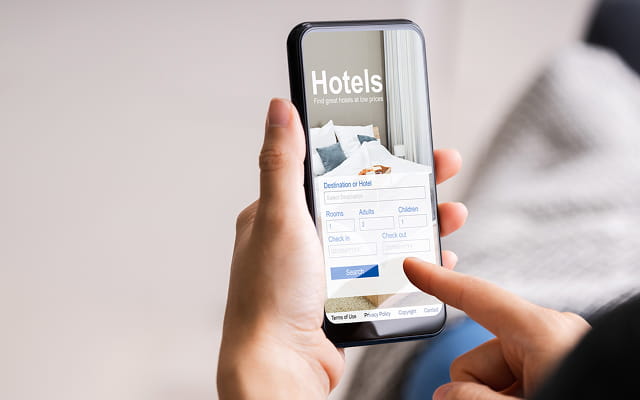 スマートフォンでホテル予約サイトを閲覧している様子を示す手元のアップ