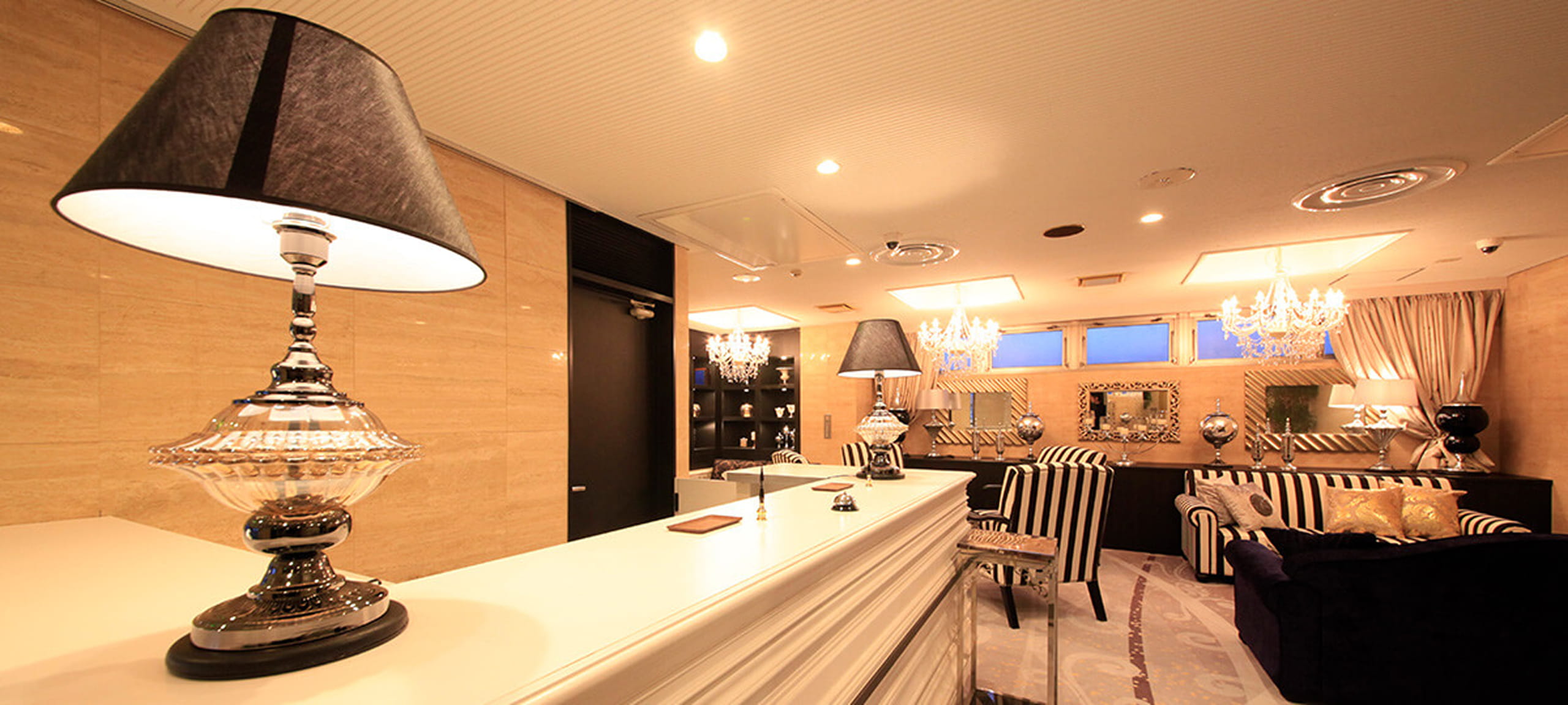 シャンデリアとストライプ柄の椅子が調和した、高級感のあるホテルのロビー空間