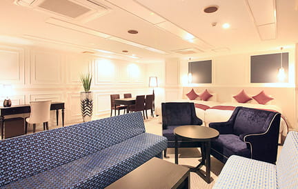 ダークブルーのソファと照明が落ち着いた雰囲気を演出する、モダンなホテルの一室