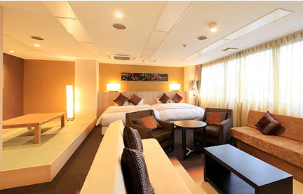 落ち着いた照明と長椅子のあるリビングスペースが印象的な、スタイリッシュなホテルの一室