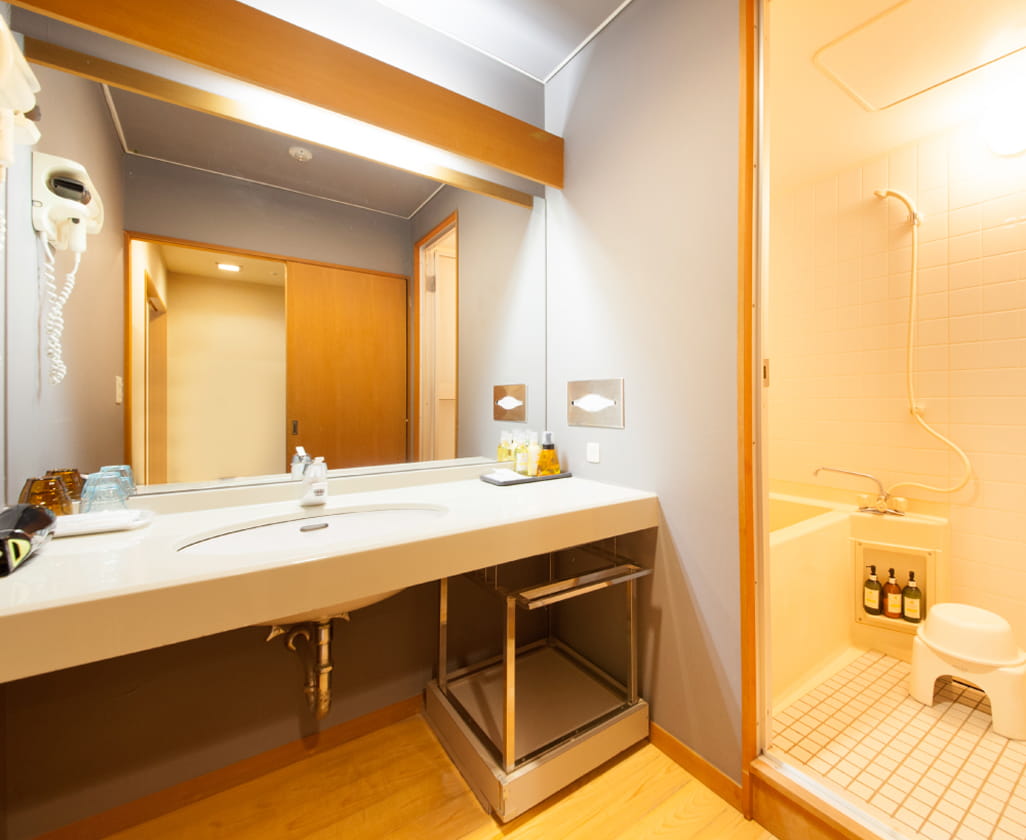 洗面台と大きな鏡が備わった、清潔感のあるホテルのパウダールーム